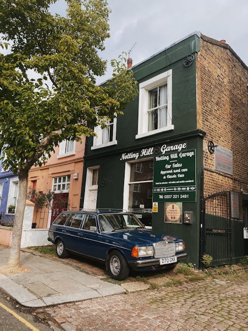 The image depicts the exterior of a multi-story building in Notting Hill with a dark green facade, featuring white-framed windows on the upper floors and a sign that reads 'Notting Hill Garage' along
